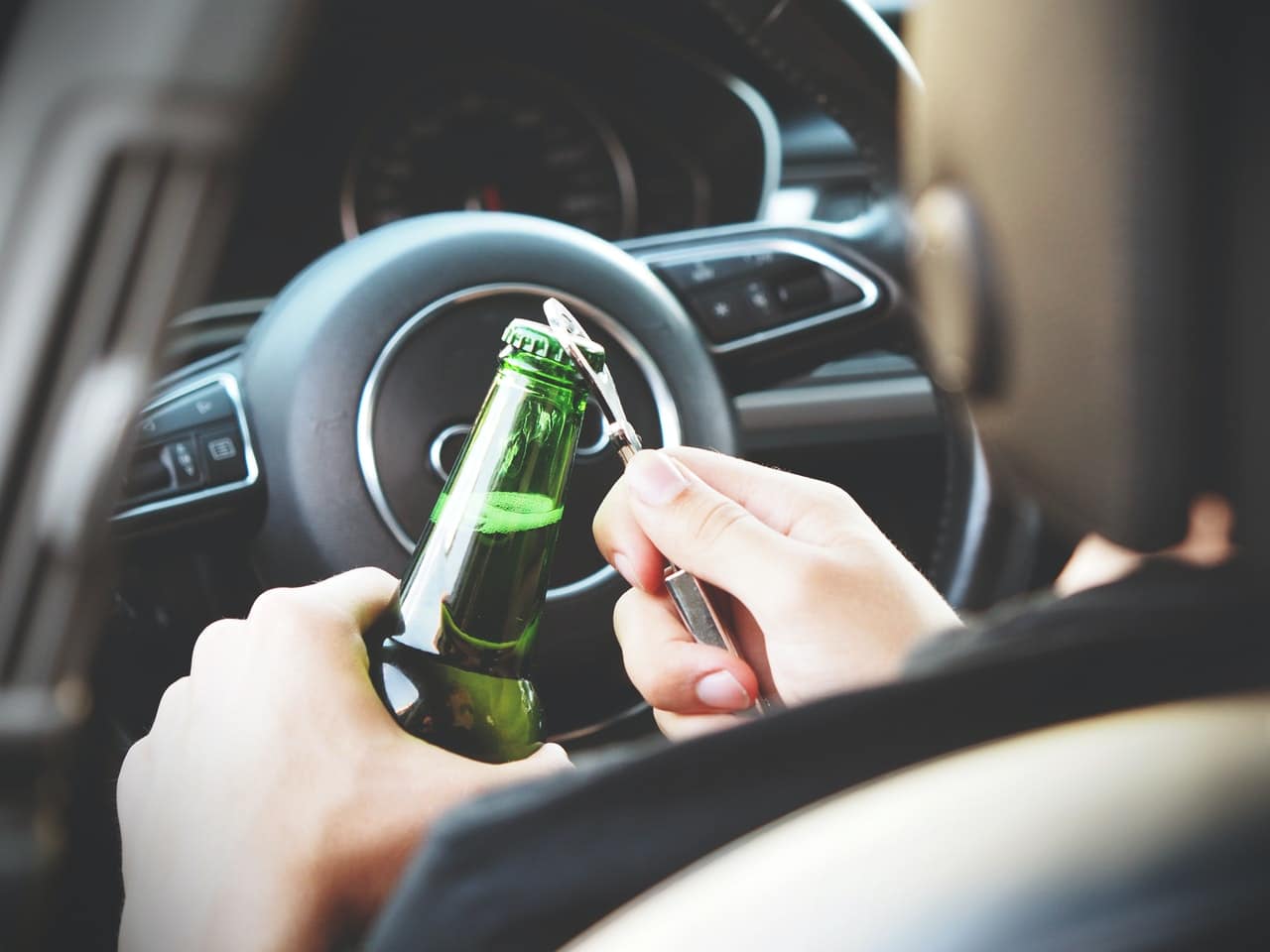 A man opening a bottle of beer about to go drink driving